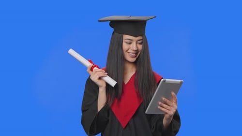 Graduate Looks at Tablet Holding Diploma