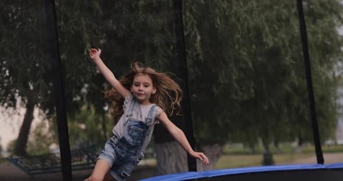 Girl Jumps on a Trampoline Outdoors