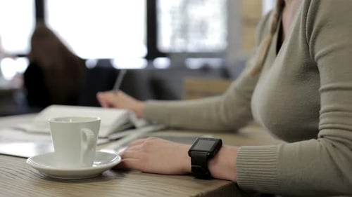 A business girl in a restaurant works with a tablet and drinks coffee.