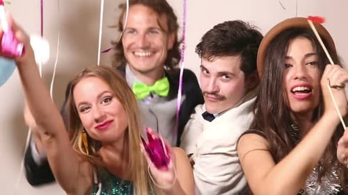 Two girls and two guys playing with props in party photo booth