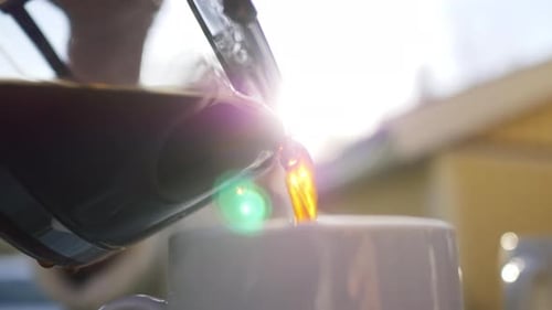 close up of coffee is poured in a cup outside house. A perfect morning with a cup of hot espresso