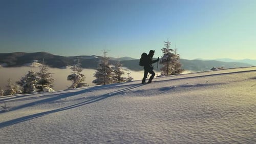 Aerial View of Backpacker Hiking Snowy Mountain Hillside on Cold Winter Day