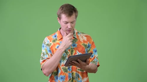 Young Adult Using Tablet in Front of Green Screen