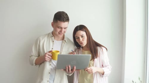 Young Couple Looks at Laptop Together Indoors