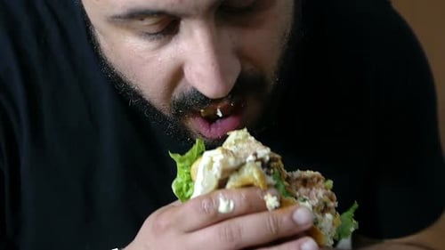 Bearded Man Enjoying a Messy Burger Close-Up
