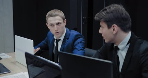 Businessmen Working Together on Laptops in Office