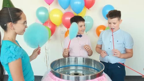Children Eat Cotton Candies Near Machine at Birthday Party
