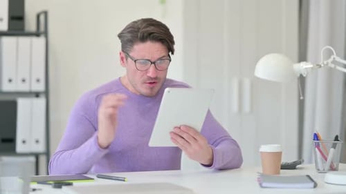 Man Reacts to Something on Tablet in Office