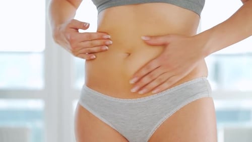 Femme enduit son estomac avec du gel contre les vergetures et fait de l'automassage