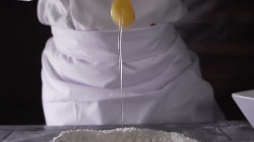 chef pouring an egg onto flour in slow motion