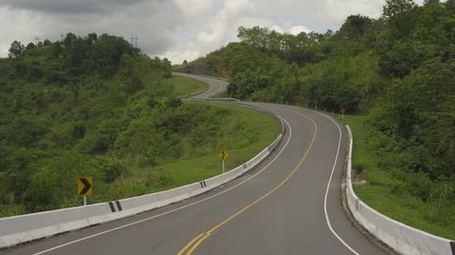 Cars driving on zigzag curve road or street on mountain hill with green natural forest