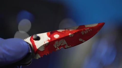 Close Up of Bloody Knife held in Gloved Hand