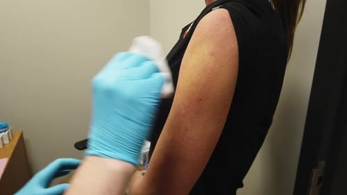 Nurse Administers A Coronavirus COVID-19 Vaccine Shot To An Adult Female Patient