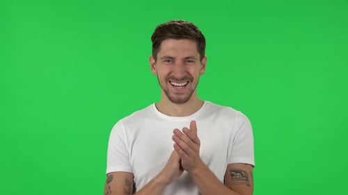 Retrato de un chico seguro aplaude con alegría y deleite felices. Pantalla verde