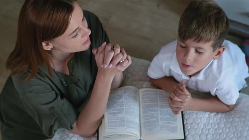 Mother and Child Praying, Reading Bible Together Indoors