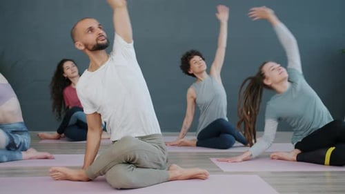 Slow Motion of Yoga Class Doing Gomukhasana Position Then Resting with Hands in Namaste