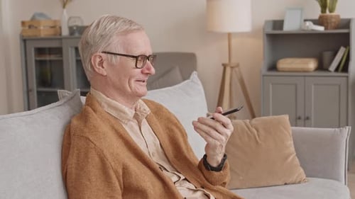 Senior Man Talking Into Smartphone on Sofa