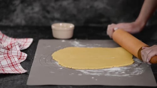 Hands Roll Dough with a Wooden Rolling Pin