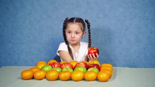 Child Eats Apple Surrounded by Fruit