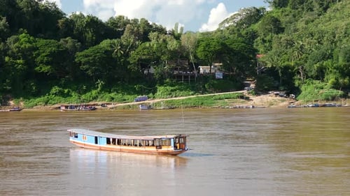 Barco de cola larga que se mueve a la altura de la corriente en el río Mekong en Luang Prabang