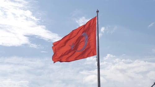 Red Flag Waving Proudly Against Cloudy Sky