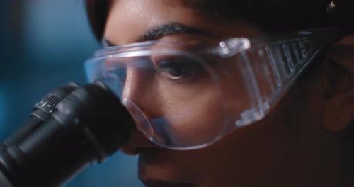 Nahaufnahme von Wissenschaftleraugen, Blick ins Mikroskop, Schutzbrille tragen