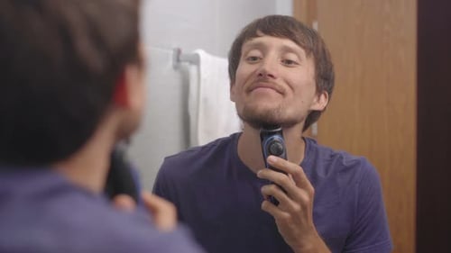 Man Trims Facial Hair in Bathroom Mirror