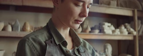 Artist Shaping Clay Sculpture in Brightly Lit Studio