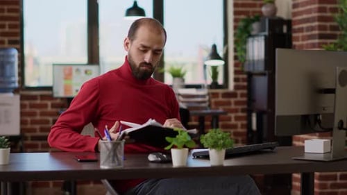 Man Reviews Business Documents in Bright Office