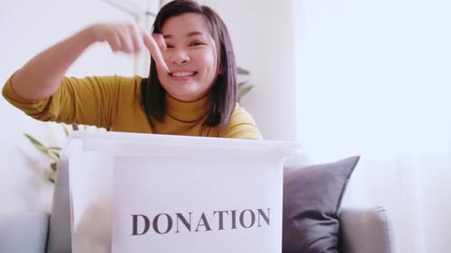 Schöne Frau, die mit Spenden auf Box zeigt und andere zum Spenden einlädt.