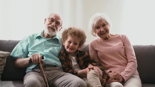 Grandparents and Grandchild Waving on Couch