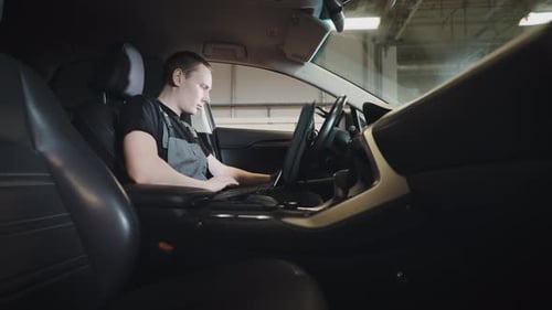 Ein Mann ist ein Mechaniker, der im Auto sitzt und eine Computerdiagnose des Motors und der Systeme durchführt
