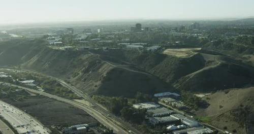 Aerial helicopter shot, overhead shot of busy LA highway, past large constuction site, deep pits and