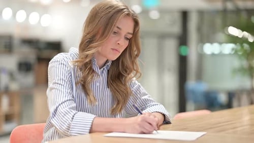Serious Businesswoman Writing on Paper in Office
