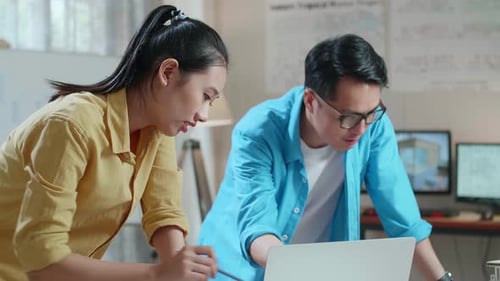Asian Woman And Man Engineers With Laptop Computer Discuss About Design At The Office
