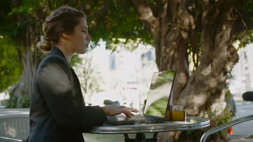 Young business woman sitting in a cafe working on a laptop computer