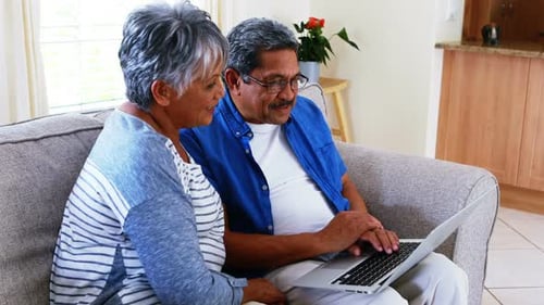 Senior Couple Relaxing on Couch Using Laptop