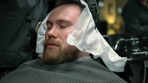 Barber Wrapping Paper Around Man's Head in Shop