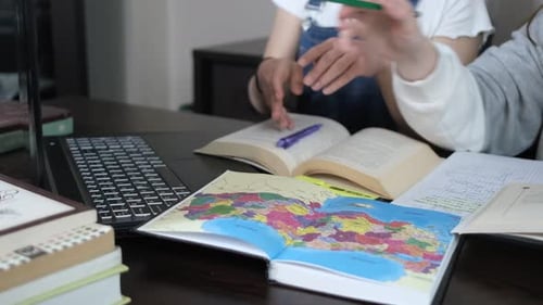 Two Students Studying Together with Map and Laptop