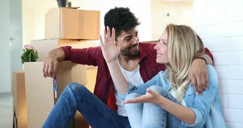 Young Happy Couple Moving in New Home and Unpacking Boxes