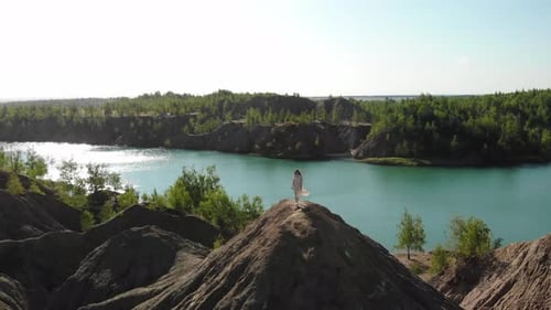 Filmansicht einer schlanken Frau in langem weißen Kleid nähert sich dem Rand des Abgrunds und breitet ihre Arme aus