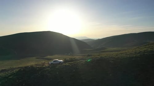 Offroad-Fahrzeug fährt bei Sonnenuntergang auf Bergen in Luftaufnahme
