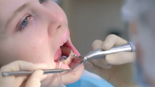 Dentist Performing Teeth Cleaning on Female Patient
