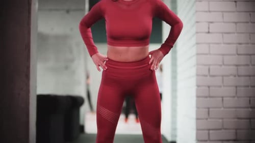 Young Woman in Red Sports Suit Doing Fitness Exercises in the Gym Bending Forwards with Her Body