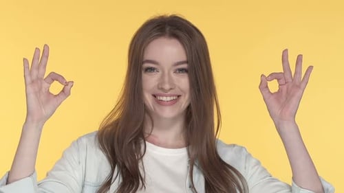 Woman Gives OK Sign on Yellow Background