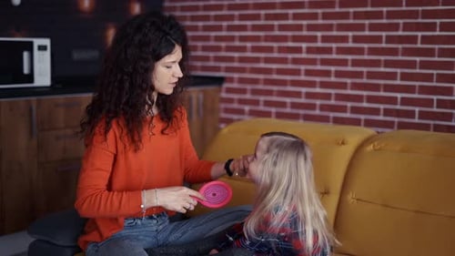 Woman Brushing Child's Hair on Yellow Sofa