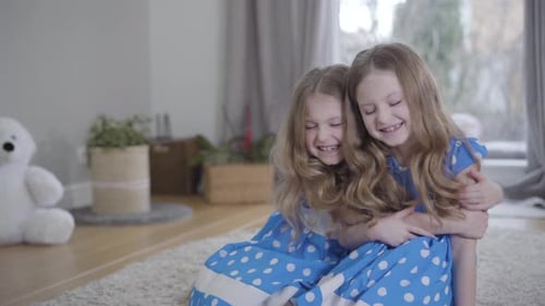 Two Young Girls Hugging and Smiling Indoors