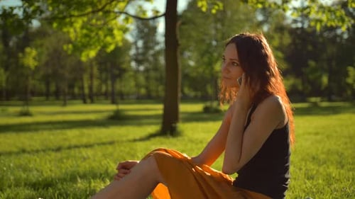 Happy Attractive Sexy Lady Sitting on Green Grass and Have Conversation Via Digital Phone.