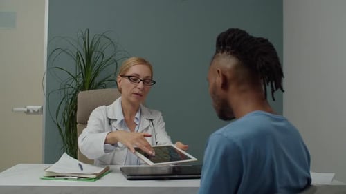 Doctor Showing Tablet Image to Patient in Office