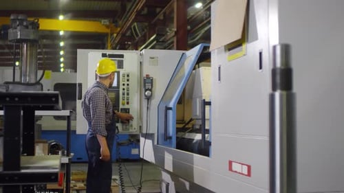 Factory worker manning large metalwork lathe